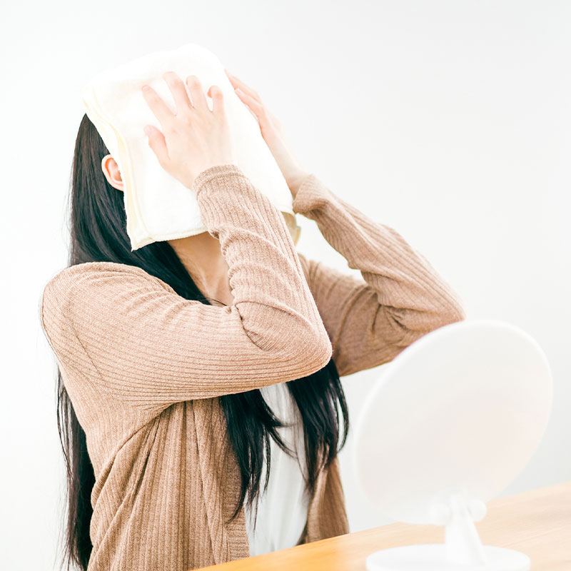 蒸しタオルを顔に乗せる女性